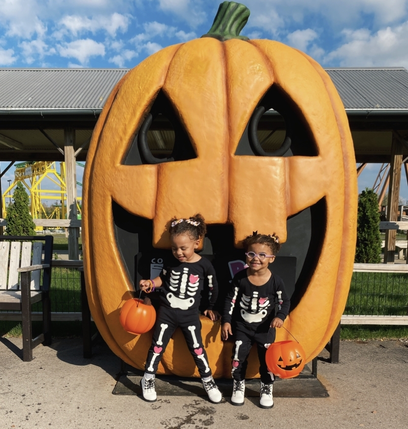 Sisters in matching skeleton pajamas in front of life sized pumpkin at Columbus Zoo.
