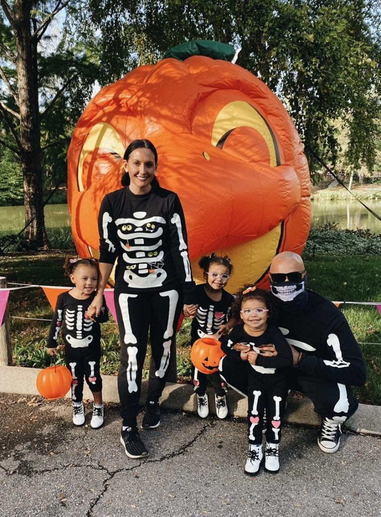 Family picture in matching skeleton pajamas in front of blow-up pumpkin at Columbus Zoo.