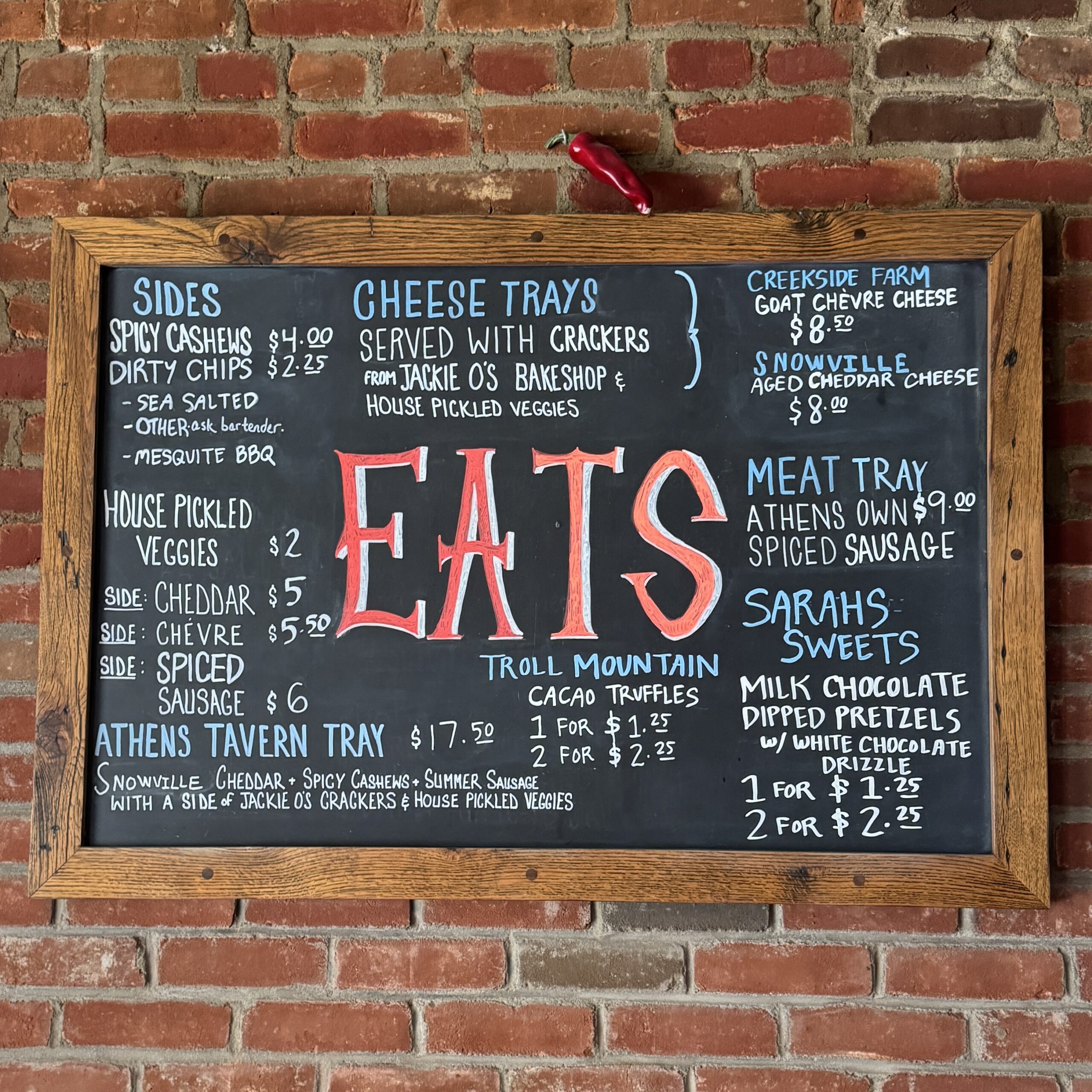 Hand-lettered chalkboard menu of eats at West End Ciderhouse in Athens, Ohio, listing cheese trays, meat trays, house-pickled veggies, and sweets